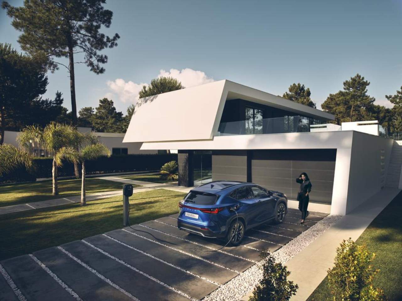 A Lexus NX plugged into a charging tower outside a home